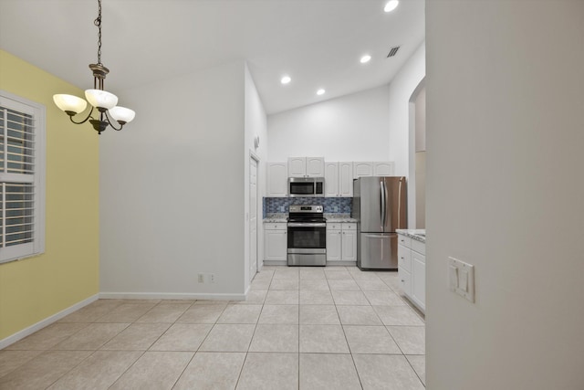 kitchen with lofted ceiling, light tile patterned floors, decorative light fixtures, white cabinetry, and stainless steel appliances