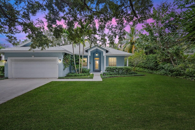 ranch-style home featuring a garage, a yard, driveway, and stucco siding