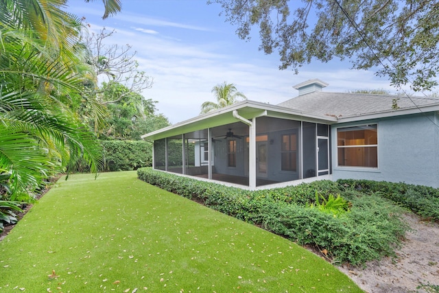 back of property with a lawn, a sunroom, and ceiling fan