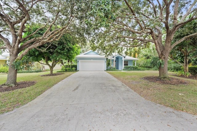 view of property hidden behind natural elements featuring a garage and a front lawn