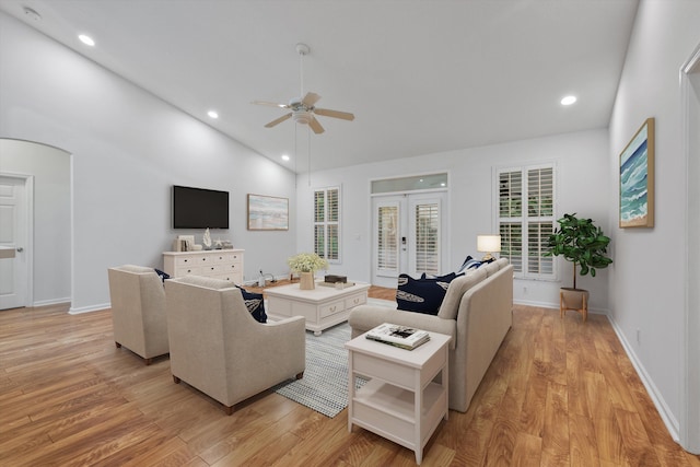 living room with ceiling fan, french doors, high vaulted ceiling, and light hardwood / wood-style floors