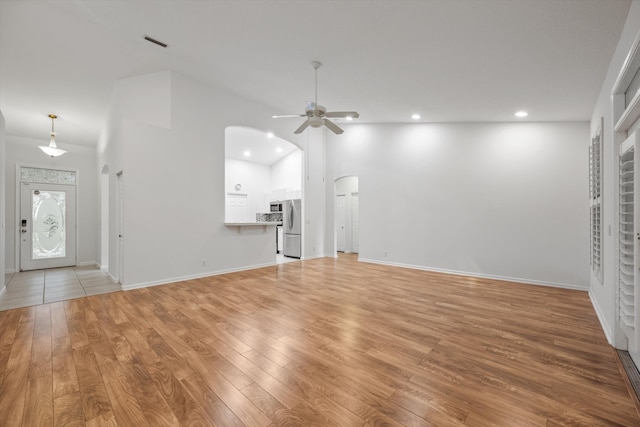 unfurnished living room with light hardwood / wood-style floors, high vaulted ceiling, and ceiling fan