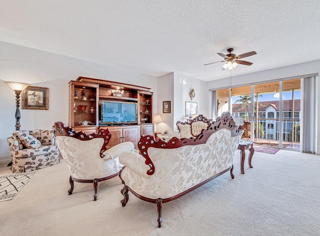 living room featuring ceiling fan, carpet floors, and a textured ceiling