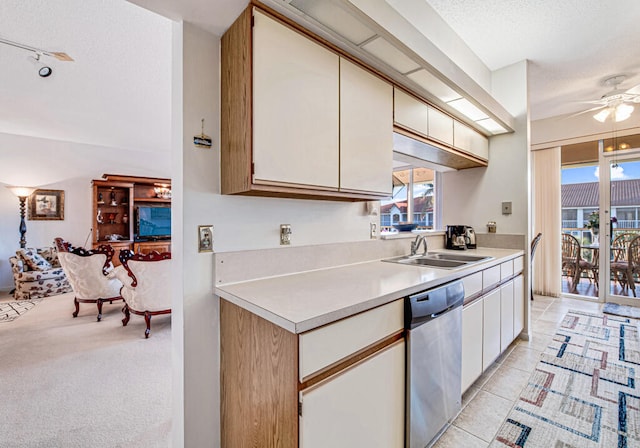 kitchen featuring dishwasher, sink, ceiling fan, a textured ceiling, and light colored carpet