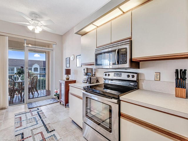 kitchen featuring appliances with stainless steel finishes, light tile patterned floors, white cabinetry, and ceiling fan