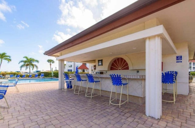 view of patio / terrace featuring exterior bar and a community pool