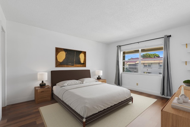 bedroom with a textured ceiling and dark hardwood / wood-style flooring