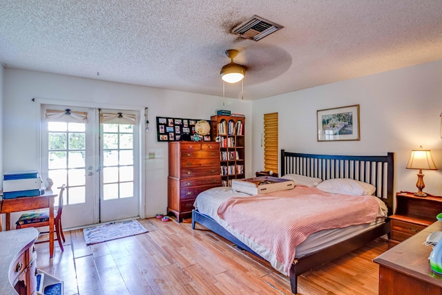 bedroom featuring french doors, a textured ceiling, access to outside, ceiling fan, and light hardwood / wood-style flooring