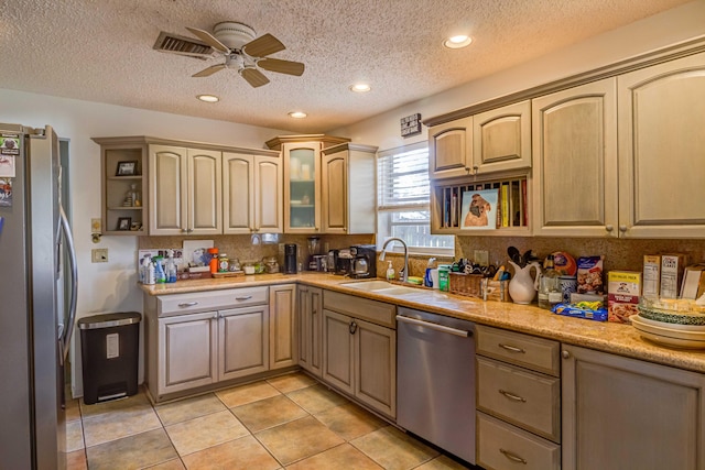 kitchen with sink, ceiling fan, light tile patterned floors, a textured ceiling, and stainless steel appliances