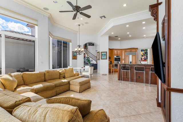 tiled living room featuring crown molding and ceiling fan with notable chandelier