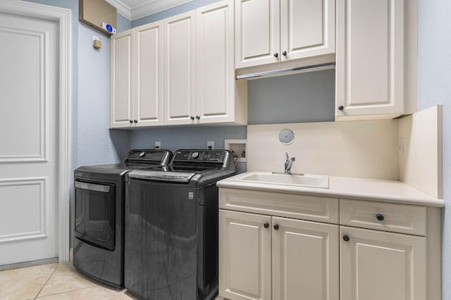 clothes washing area featuring cabinets, sink, ornamental molding, light tile patterned floors, and washing machine and clothes dryer