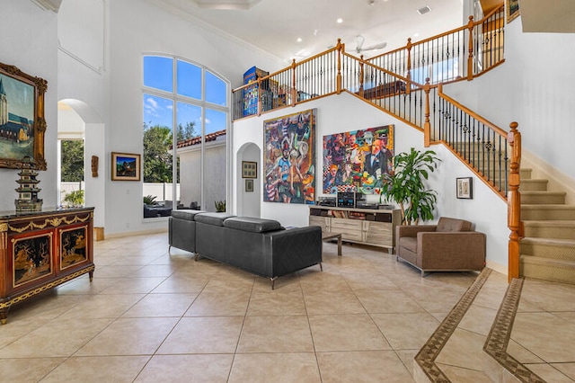 living room with a towering ceiling, light tile patterned floors, and ornamental molding