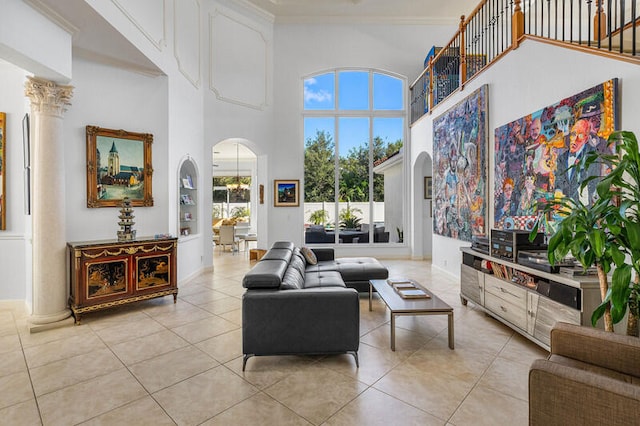 living room featuring ornate columns, light tile patterned flooring, a high ceiling, and ornamental molding