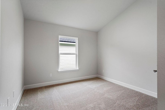 carpeted spare room featuring lofted ceiling