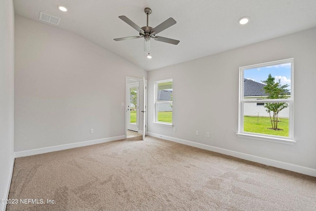 empty room featuring carpet, lofted ceiling, ceiling fan, and a healthy amount of sunlight