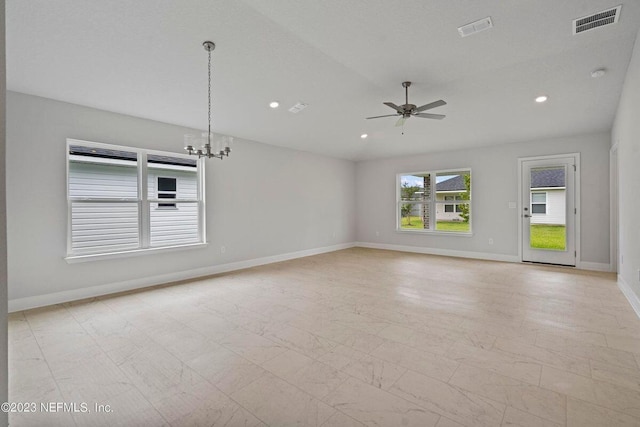 spare room featuring ceiling fan with notable chandelier