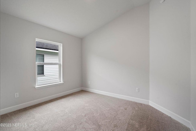 carpeted empty room featuring lofted ceiling