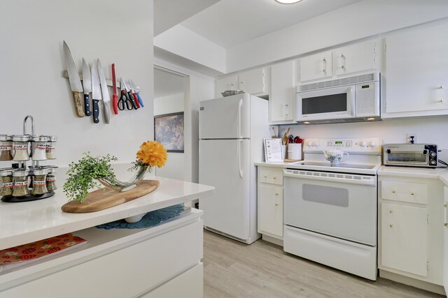 kitchen with white cabinetry, sink, dark hardwood / wood-style floors, and white appliances