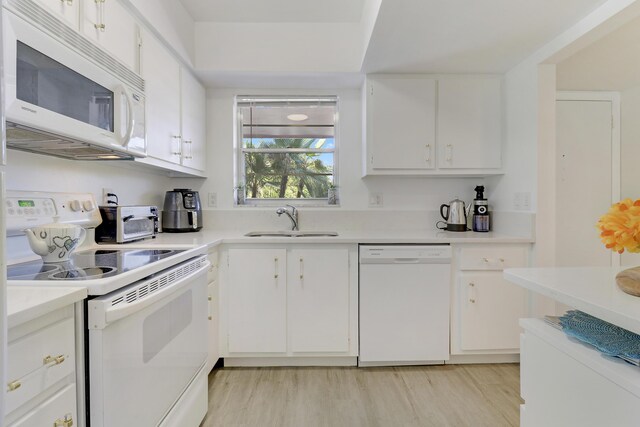 kitchen with white cabinets, white dishwasher, light hardwood / wood-style floors, and sink