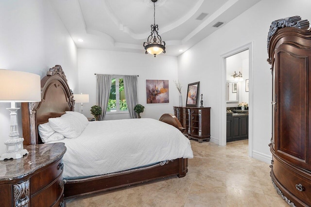 bedroom featuring a raised ceiling and ensuite bath