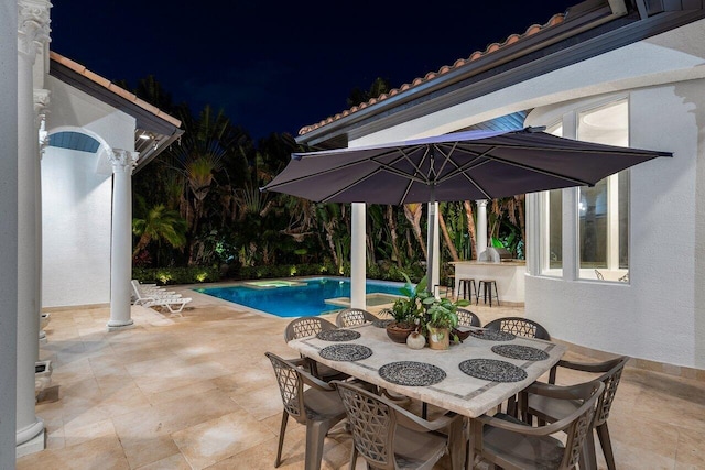 pool at twilight with a patio area and a bar