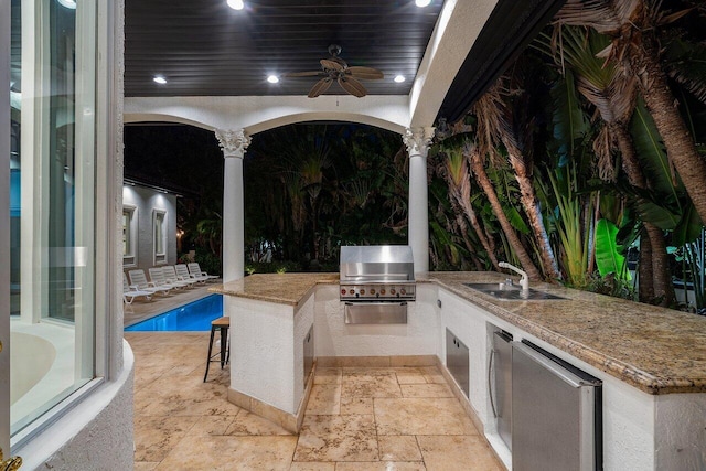 view of patio with an outdoor kitchen, ceiling fan, a wet bar, and grilling area