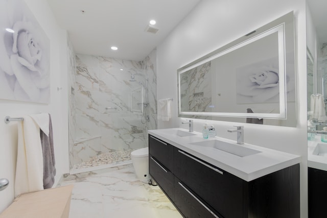 bathroom with a tile shower, vanity, and toilet