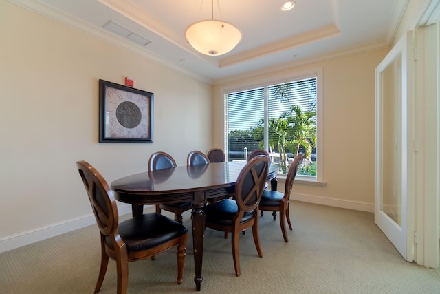 carpeted dining room with a raised ceiling and ornamental molding