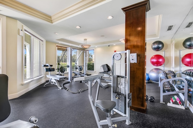 workout area with a raised ceiling, plenty of natural light, and ornamental molding