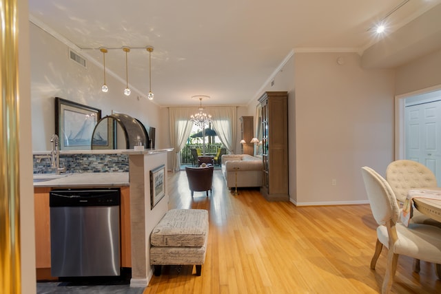 kitchen with ornamental molding, pendant lighting, light hardwood / wood-style flooring, dishwasher, and a chandelier