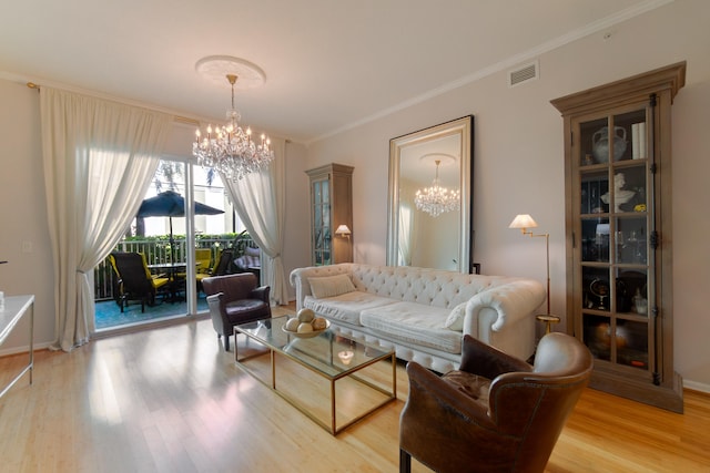 living room with light wood-type flooring, ornamental molding, and an inviting chandelier