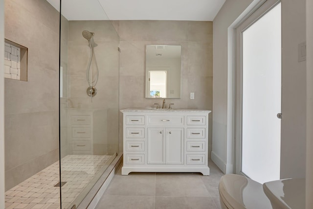 bathroom with tile patterned flooring, vanity, tile walls, and walk in shower