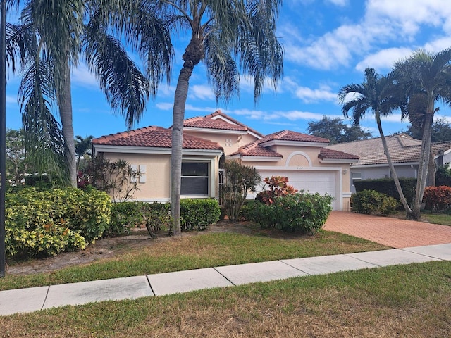 mediterranean / spanish house with a garage and a front lawn