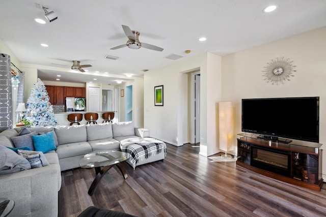 living room featuring ceiling fan and dark hardwood / wood-style flooring