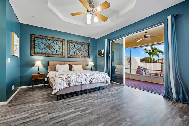 bedroom with hardwood / wood-style floors, a closet, a raised ceiling, and ceiling fan