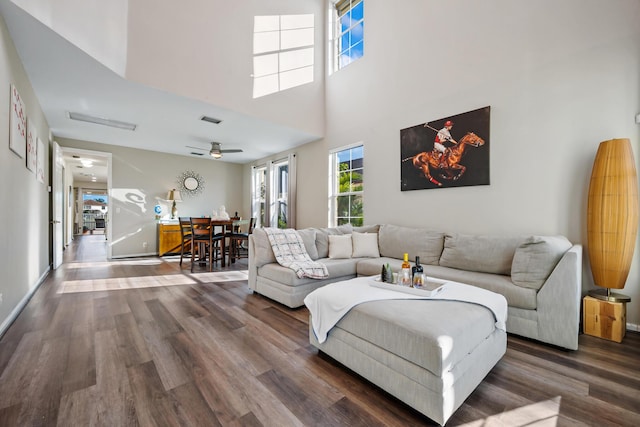 living room featuring ceiling fan, dark wood-type flooring, and a high ceiling