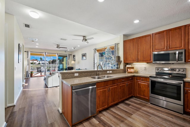 kitchen featuring hardwood / wood-style flooring, kitchen peninsula, sink, and appliances with stainless steel finishes