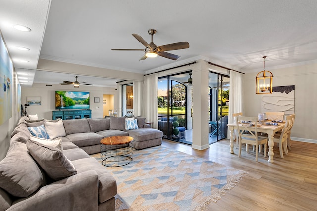 living room featuring ceiling fan with notable chandelier, light wood-type flooring, and crown molding