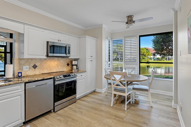 kitchen featuring white cabinetry, a water view, a healthy amount of sunlight, and appliances with stainless steel finishes