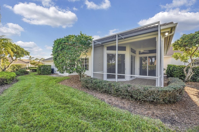 exterior space featuring a lawn, glass enclosure, and ceiling fan