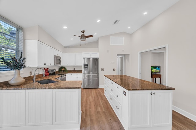 kitchen with stainless steel appliances, sink, light hardwood / wood-style floors, white cabinetry, and lofted ceiling