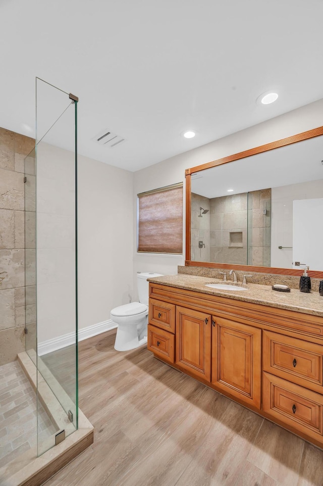 bathroom with hardwood / wood-style flooring, vanity, toilet, and an enclosed shower