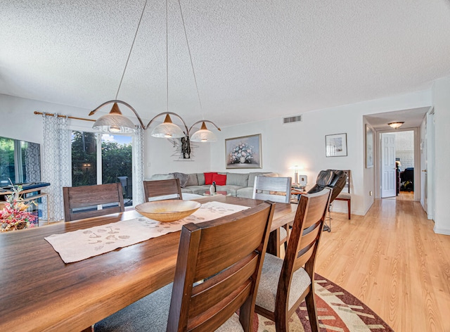 dining area with a textured ceiling and light wood-type flooring