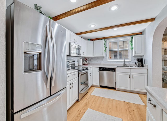 kitchen featuring white cabinets, sink, light hardwood / wood-style flooring, beam ceiling, and stainless steel appliances