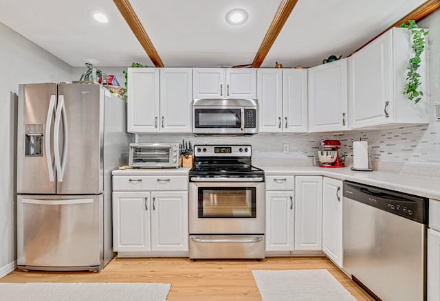 kitchen featuring appliances with stainless steel finishes, light wood-type flooring, white cabinetry, and backsplash