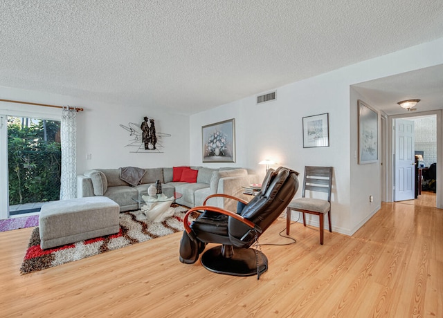 living room featuring light hardwood / wood-style flooring and a textured ceiling