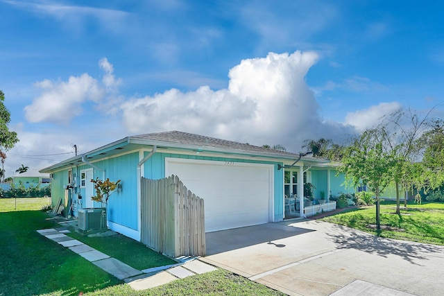 view of front of property featuring cooling unit, a front yard, and a garage