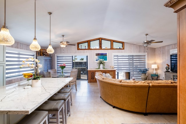 tiled living room featuring ceiling fan, wooden walls, and vaulted ceiling