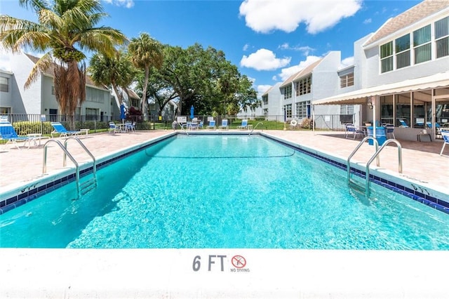 community pool with a patio area, a residential view, and fence