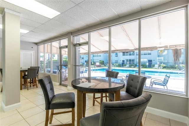 interior space with a paneled ceiling, baseboards, and light tile patterned floors